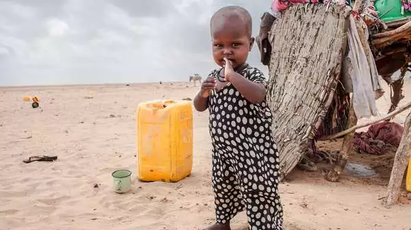 Ein Kleinkind steht vor einem Zelt in der Wüste während einer extremen Dürreperiode, Somaliland 2017. 
