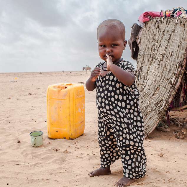 Ein Kleinkind steht vor einem Zelt in der Wüste während einer extremen Dürreperiode, Somaliland 2017. 