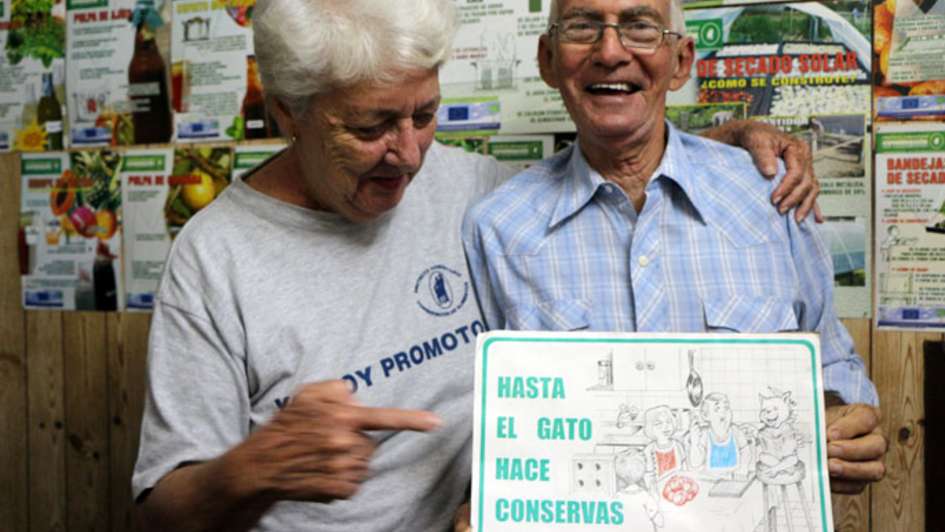 Two persons holding a sign saying "Hasta El Gato Hace Conservas"