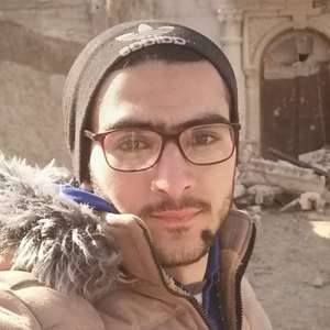Mann macht Selfie vor eingestürzten Häusern in Syrien.