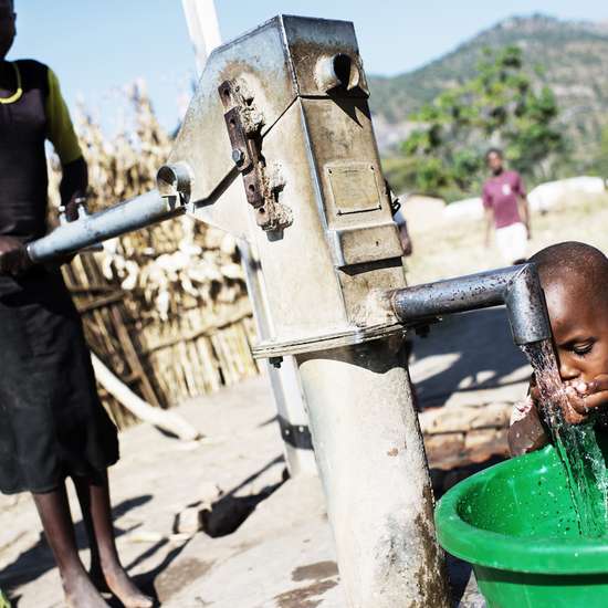 Junge trinkt Wasser an Brunnen.