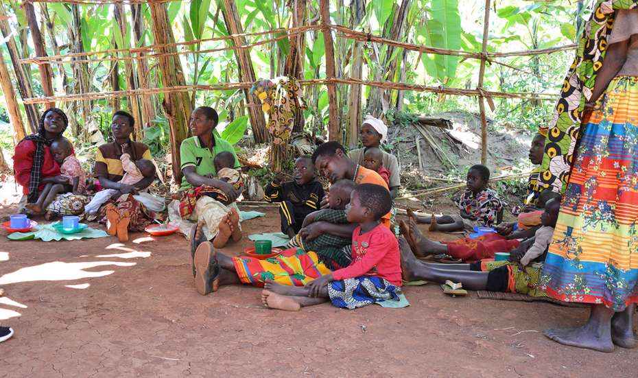 Burundi-Hilfe - Bild: Mehrere Frauen und Kinder sitzen auf dem Boden und Essen.