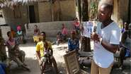 Gemeindemitglieder im Bezirk Bonthe, Sierra Leone, erhalten Informationen über Verhaltensweisen, die dazu beitragen, die Übertragung des Virus zu verlangsamen.