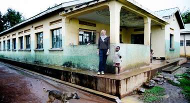 Schauspielerin Gesine Cukrowski mit einem kleinen Kind vor einem Krankenhaus in Uganda 