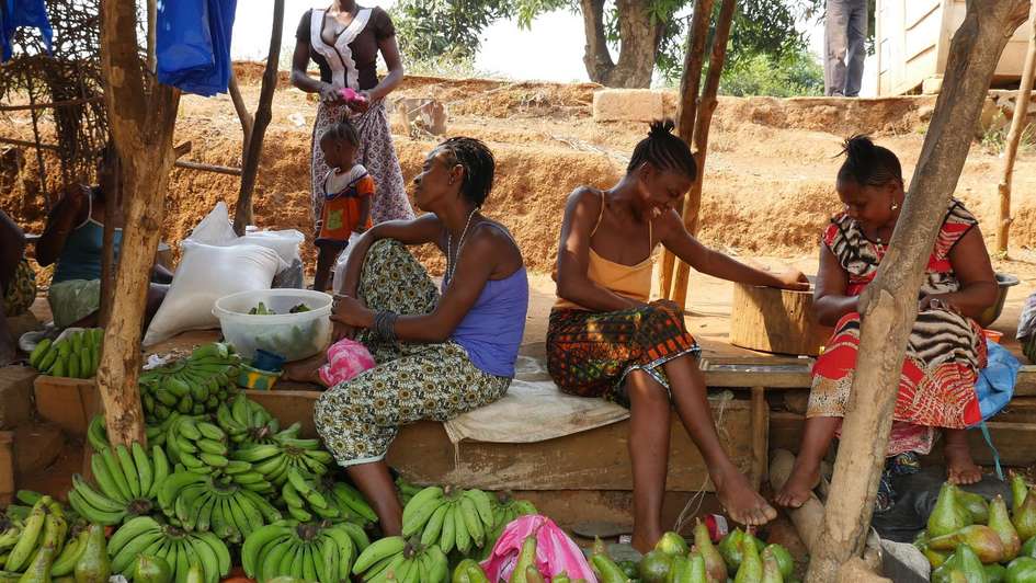 Marktfrauen sitzen an ihrem Stand und verkaufen Früchte