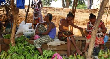 Marktfrauen sitzen an ihrem Stand und verkaufen Früchte