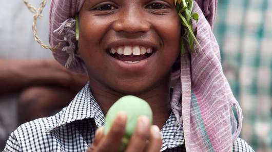 Der achtjährige Jalia Pacharia hält sein Lieblingsessen in die Höhe: einer wilde Gurke. Die Paharia im indischen Dorf Ketokuria sammeln seit jeher Dutzende Sorten wilder Waldgewaechse wie Knollen, Wurzeln, Früchte und Gemüse, doch durch Waldrodungen, finden sie immer weniger Essbares. Der Welthungerhilfe-Partner CWS/Avibyakti Foundation hilft ihnen, die Vielfalt zu erhalten. 