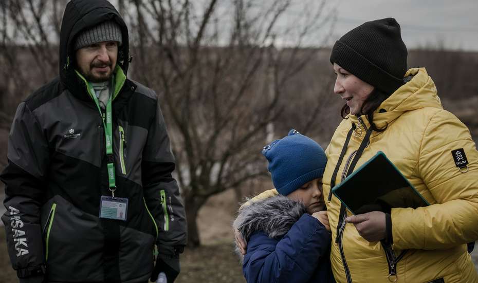 Eine Mutter, ihre Tochter und Mitarbeiter der Welthungerhilfe in warmer Winterkleidung