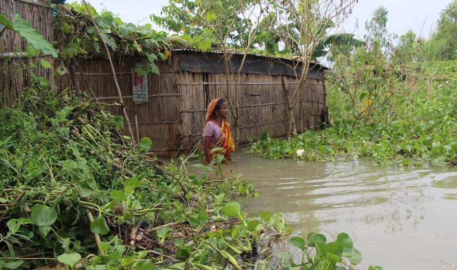 Eine Frau steht vor ihrem Haus in tiefem Wasser