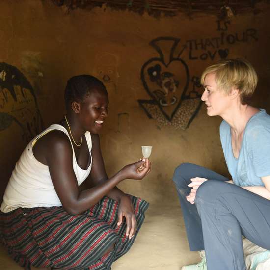 Gesine Cukrowski lässt sich in Uganda die Vorteile von Menstruationstassen erklären.