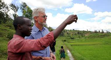 Evaluator Kai Seebörger lässt sich von einem jungen Agronom die Reisfelder der Kooperative Coriki in Ruanda erklären. 