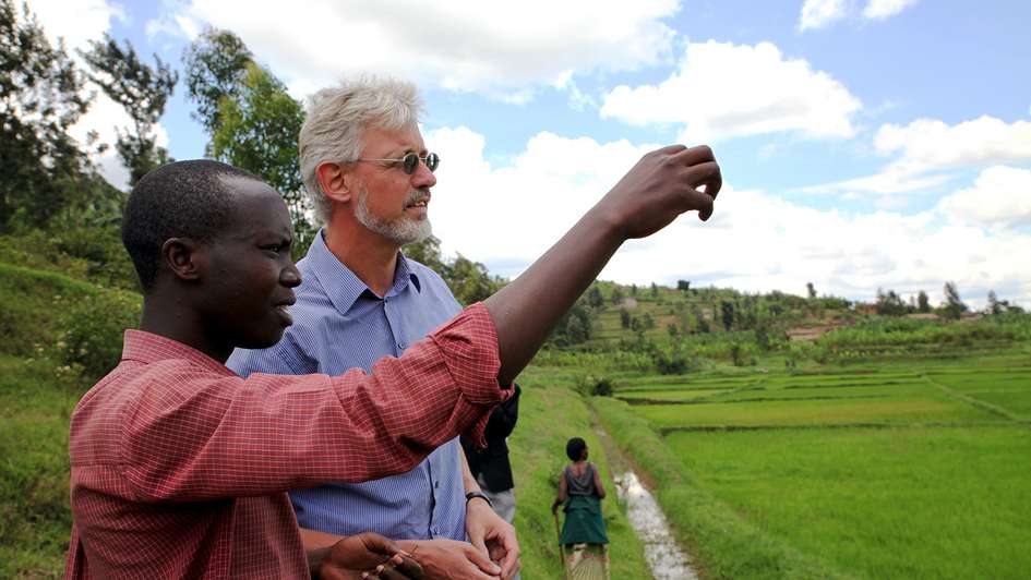 Evaluator Kai Seebörger lässt sich von einem jungen Agronom die Reisfelder der Kooperative Coriki in Ruanda erklären. 