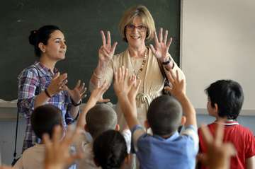 Bärbel Dieckmann steht vor einer Schulklasse für Flüchtlingskinder und zeigt 8 Finger © Grossmann