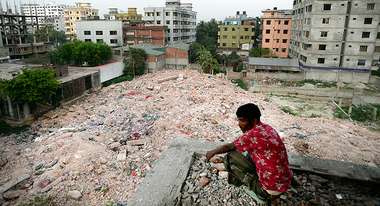 Ein Mann sitzt in der Hocke und schaut auf die Trümmer eines Gebäudes