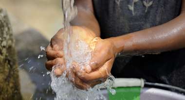 Kind schöpft Wasser mit den Händen