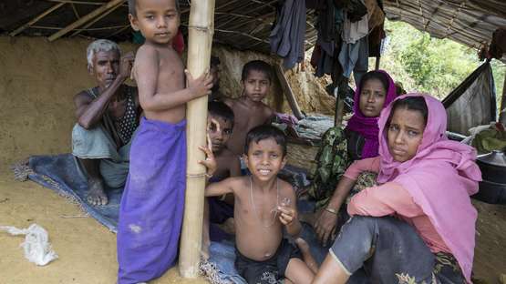 Jetzt für Flüchtlinge spenden. Bildbeschreibung: Eine Familie in einer überdachten Unterkunft in einem Flüchtlingscamp in Bangladesch.