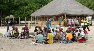 Dorfbewohner sitzen versammelt auf dem Boden