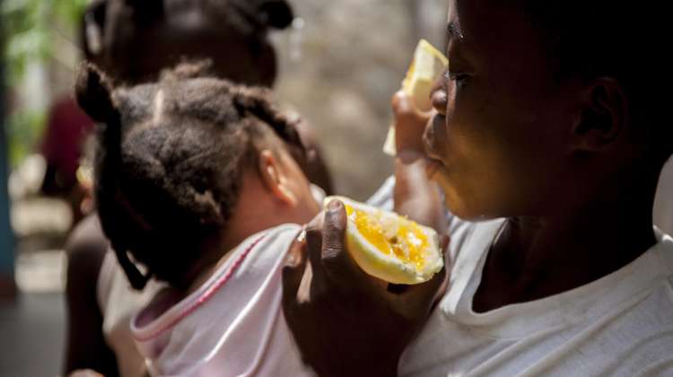 Mutter und Kind in Haiti genießen frische Orangen.
