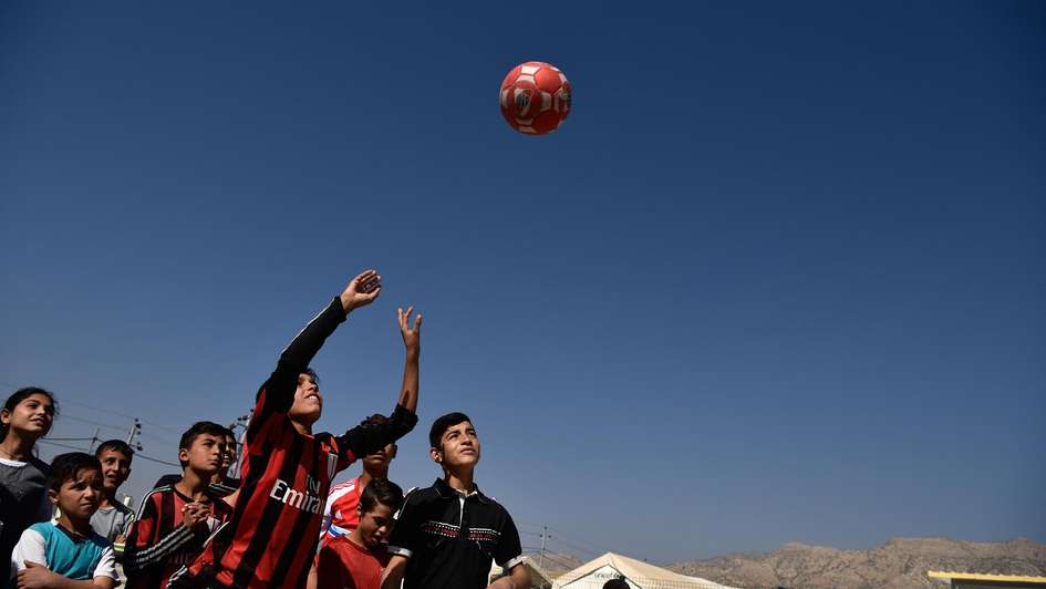 Jesidische Kinder werfen Ball in die Luft