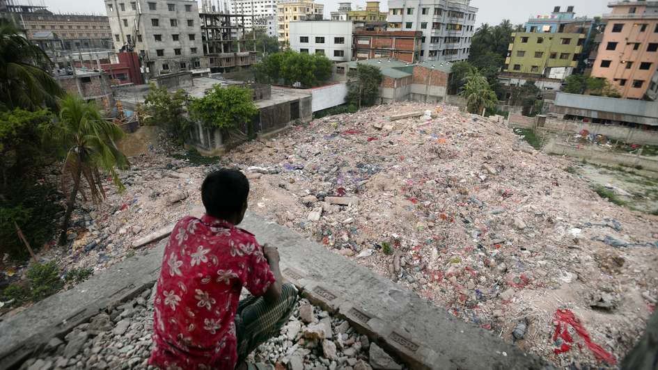 Ein Mann sitzt vor den Trümmern der Textilfabrik Rana Plaza in Bangladesch.