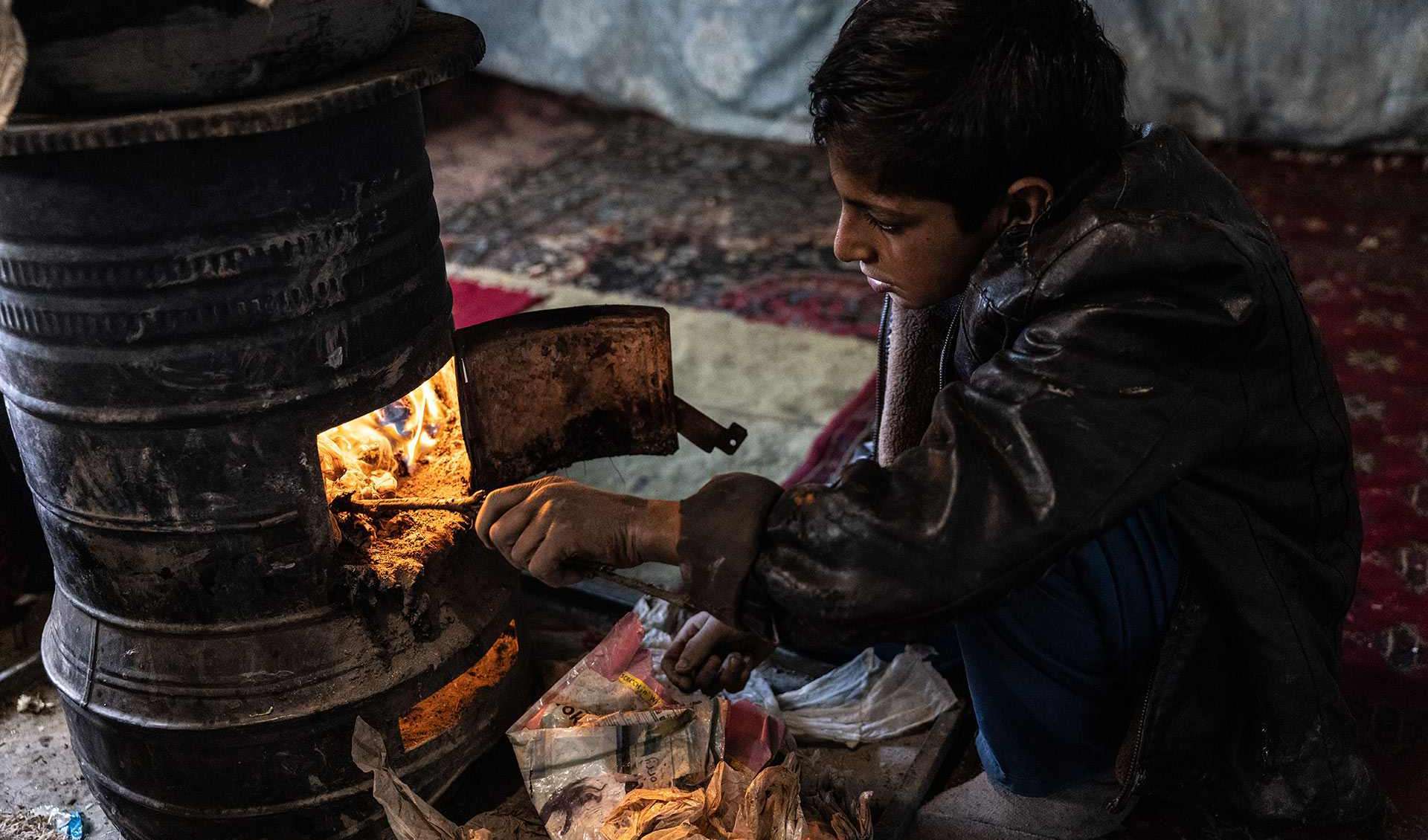 Der 10-jährige Noor aus Kabul heizt den Ofen an, den die Familie zum Kochen verwendet und gleichzeitig zum Heizen des Hauses. Holz oder Kohle können sie sich nicht leisten. 