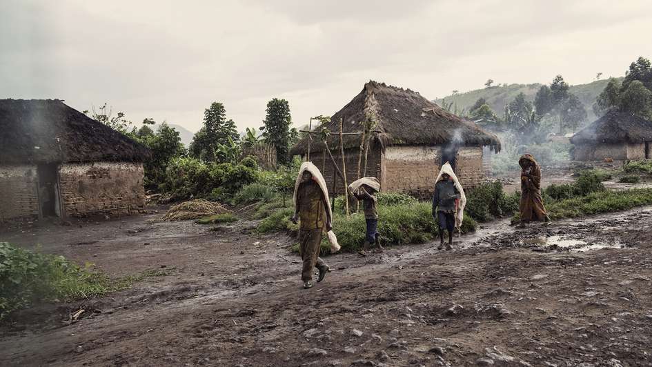 Menschen gehen auf einer ungeteerten Straße im Kongo.