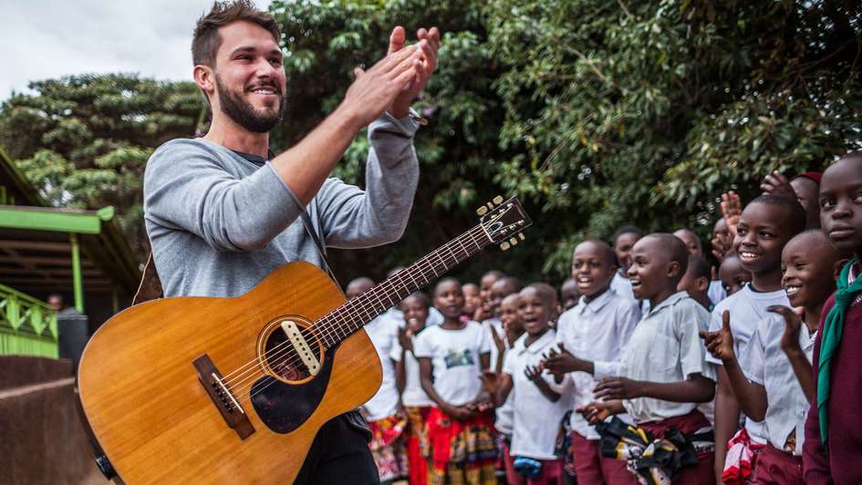 Sänger und Songwriter Robert Redweik mit Gitarre bei seinem Besuch des "Skill up!"-Projekts der Welthungerhilfe in Kenia.