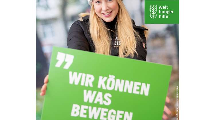 Nina Ensmann hält ein grünes Schild, darauf steht: "Wir können was bewegen."