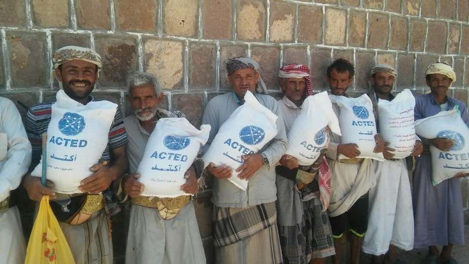 Männer halten Säcke mit Saatgut, die die Organisation ACTED verteilt hat.