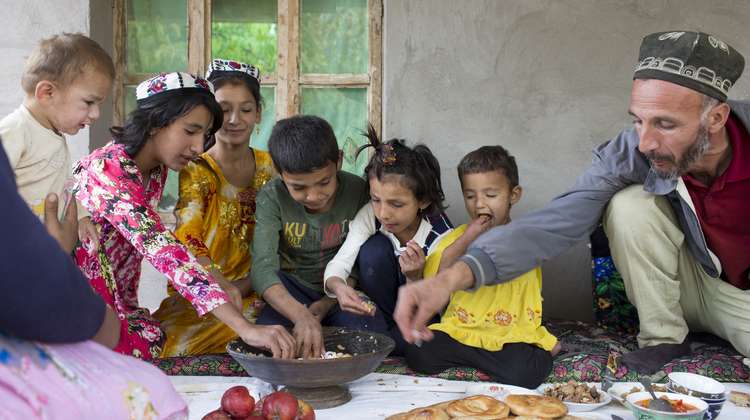 Die Großfamilie Jatimov sitzt zum Mittagessen vor ihrem Wohnhaus in Sari Hussor, Tadschikistan.