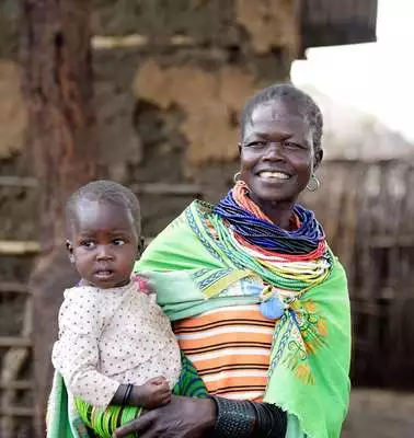 Eine lachende Frau mit einem Baby auf dem Arm.