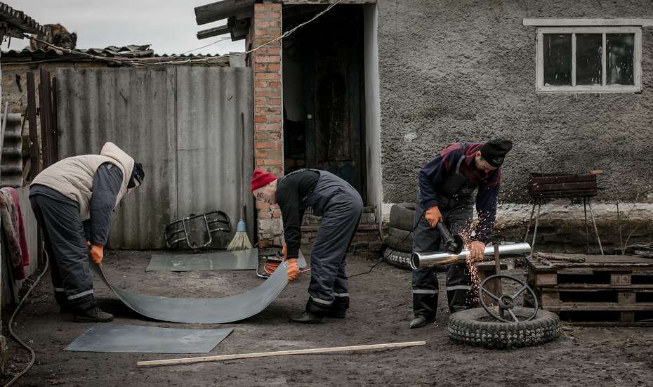 Drei Handwerker arbeiten vor dem Haus an Teilen einer Küche, die sie später einbauen werden.