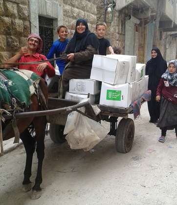 Eine Familie transportiert ihre Hilfspakete auf einer Kutsche.