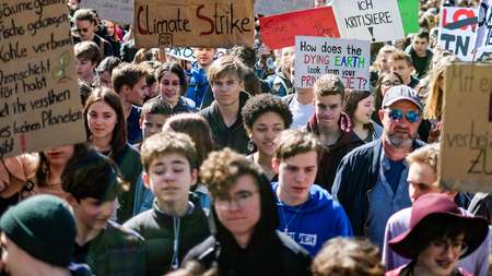 Schülerinnen und Schüler demonstrieren und halten Schilder hoch