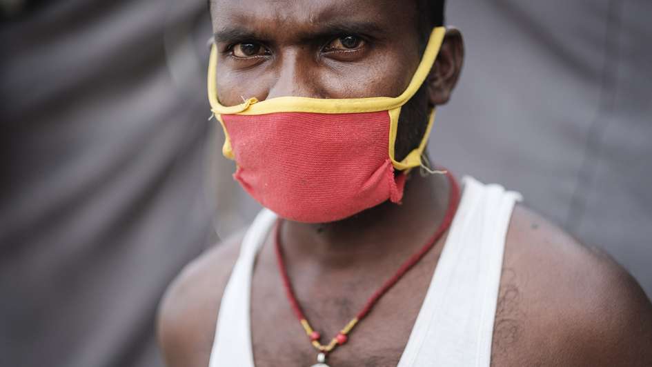 Ein Mann mit einer Maske, wie sie während Corona-Pandemie notwendig ist, schaut ernst in die Kamera.