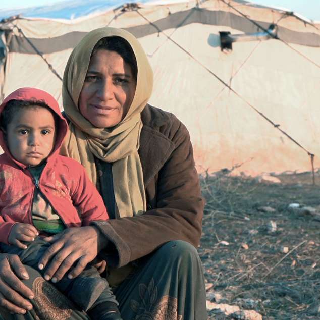 Winterhilfe in Syrien: Eine Mutter sitzt mit ihrem Kind auf der Erde