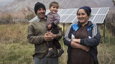 Eine Familie vor ihrer Solaranlage in Tadschikistan.