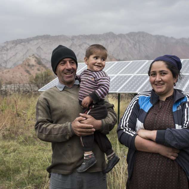 Eine Familie vor ihrer Solaranlage in Tadschikistan - jetzt für Tadschikistan spenden und mehr Menschen eine Versorgung mit Strom und Wasser ermöglichen.