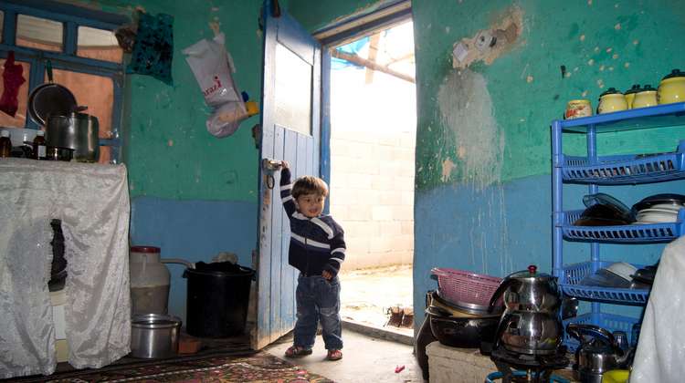Ein Kind steht in der Tür eines Zimmers in einer Flüchtlingsunterkunft