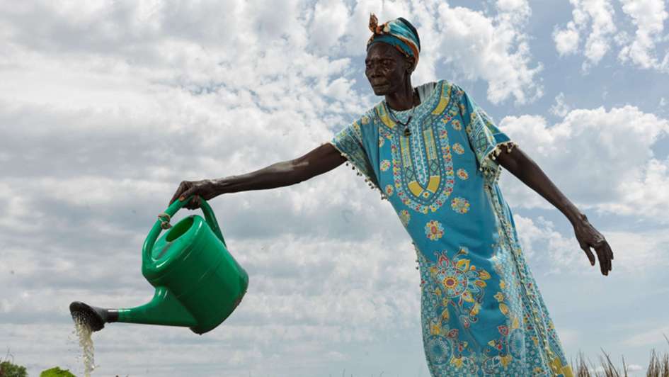 Eine Frau bewässert das Obst und Gemüse in dem schuleigenen Garten, Südsudan 2022.
