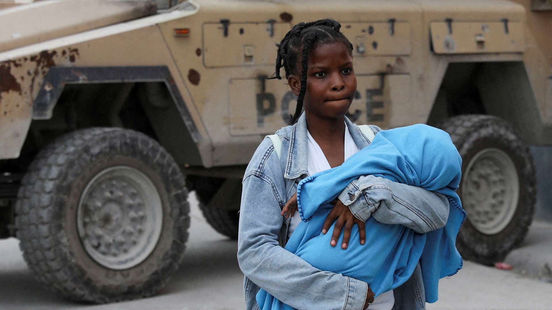 Eine junge Frau in Port-au-Prince, Haiti, verlässt mit ihrem Baby im Arm ihr Zuhause auf der Flucht vor Bandengewalt.
