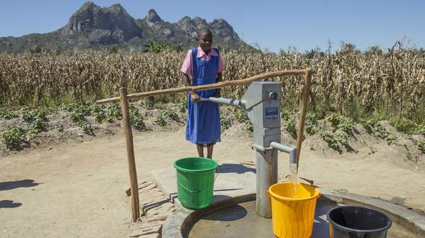 Mädchen holt Wasser an der Wasserpumpe