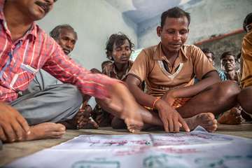 Santosh Kamder sitzt mit anderen indischen Bauern auf dem Boden. Alle lernen gemeinsam.