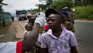 Passanten am Ebola- Checkpoint "Mile 4", die Koerpertemperatur wird gemessen.