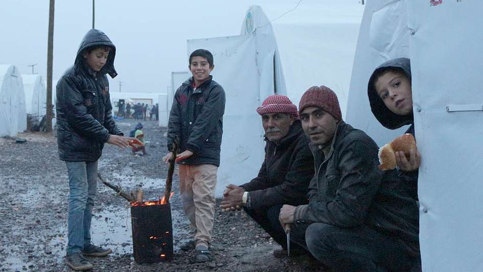 Syrische Flüchtlinge in einem Lager, zwei Kinder wärmen sich an einem Feuer