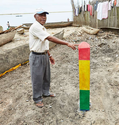 Ein Mann zeigt einen dreifarbigen Balken, der im Sand befestigt ist.