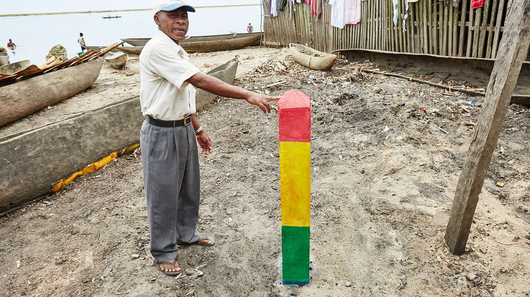 Ein Mann zeigt einen dreifarbigen Balken, der im Sand befestigt ist.