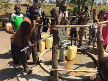 Eine Frau pumpt Wasser aus einem Brunnen.