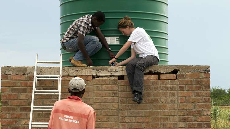Farmer Innocent Chifamba, Rodney Mushongachiware von APT und Anne-Catrin Hummel von der Welthungerhilfe schließen gemeinsam den neuen Wassertank an.