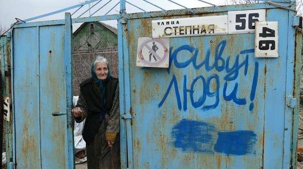 Eine ältere Dame steht in der Tür und ist verwundet; das Bild steht für Spenden für die Ukraine, 2022.